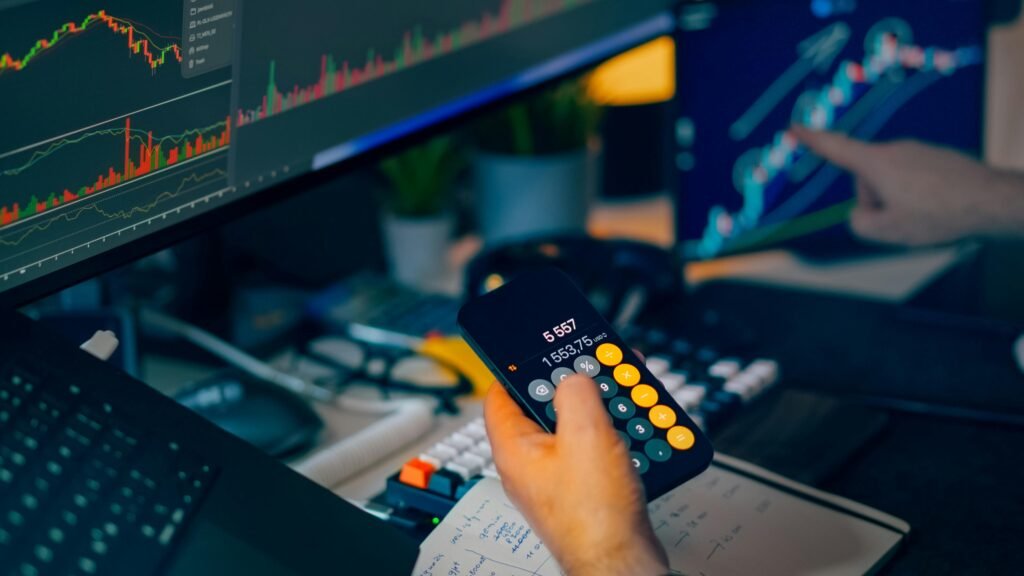 A focused shot of financial trading with screens, calculator, and data charts.