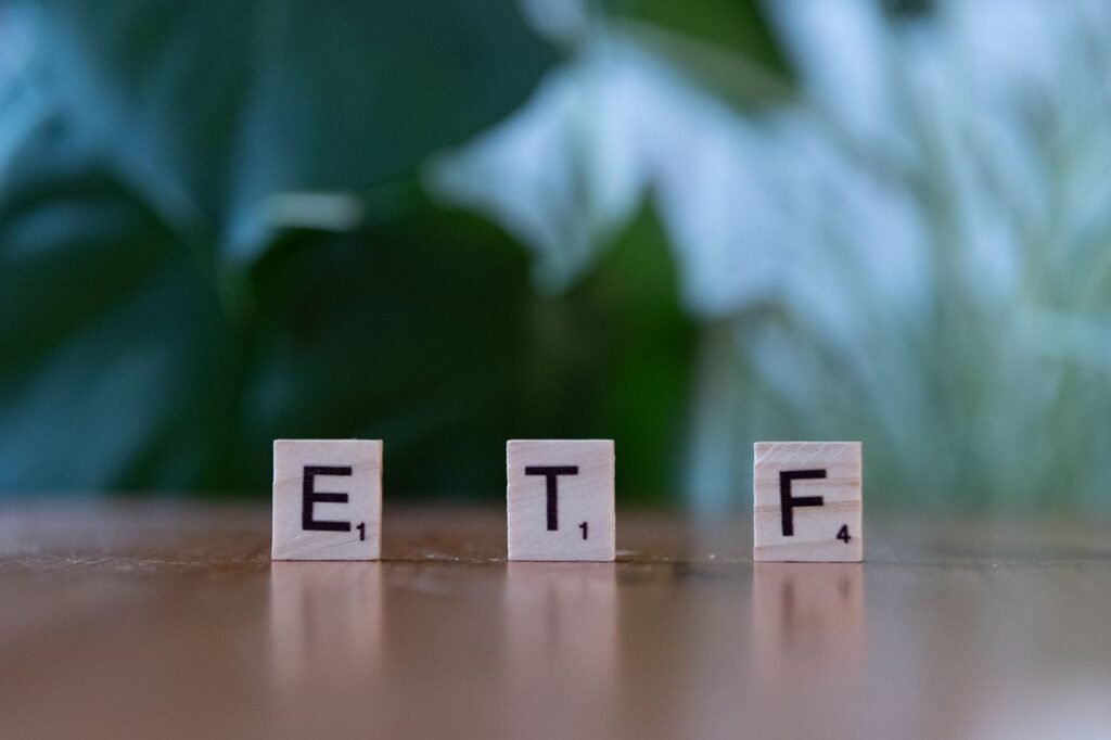 Best Canadian ETFs for Beginners (2026): A Simple Strategy to Start Investing Scrabble tiles spelling ETF on a wooden surface with blurred green background.